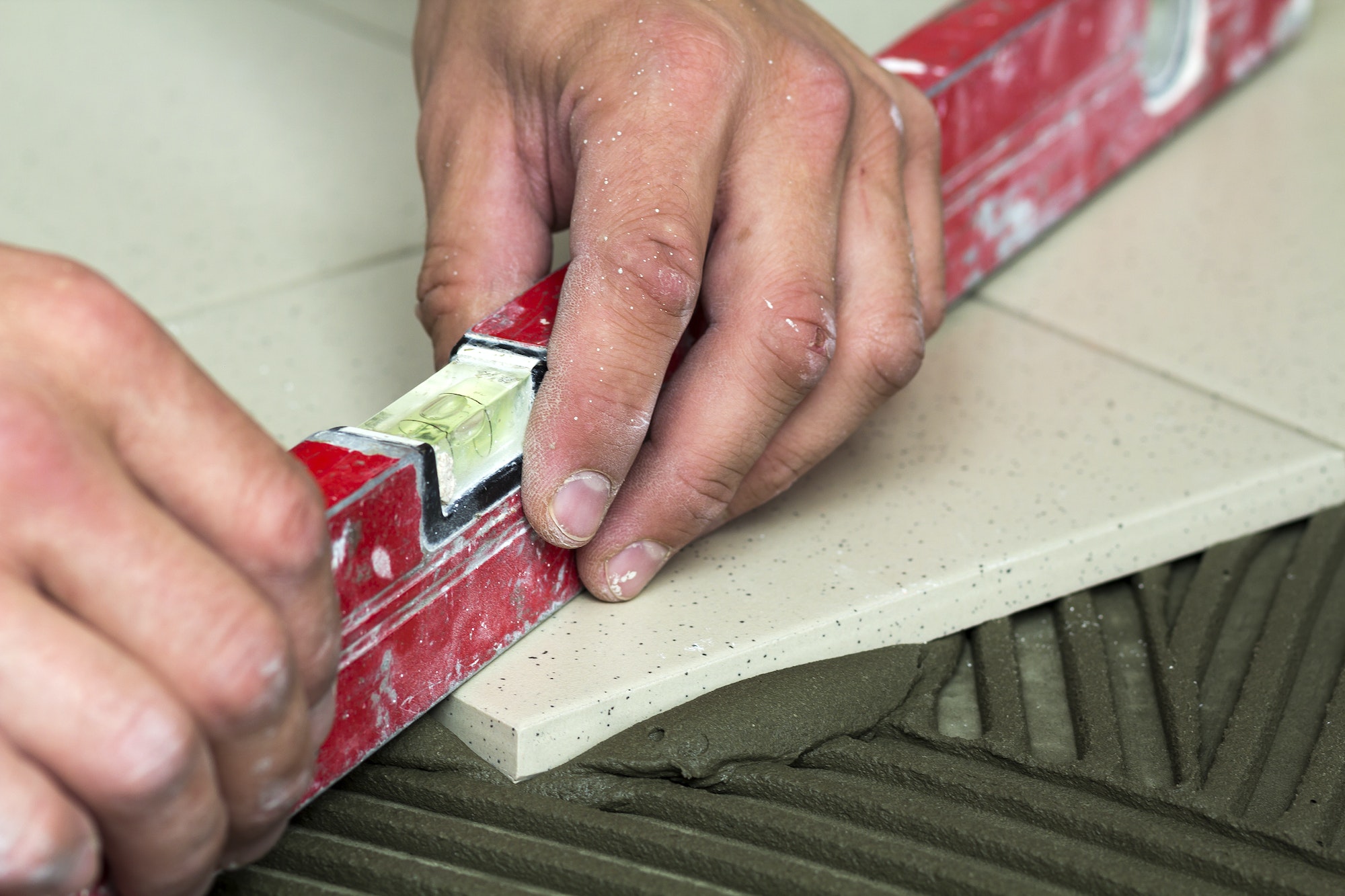 Ceramic tiles and tools for tiler. Worker hand installing floor tiles. Home improvement, renovation
